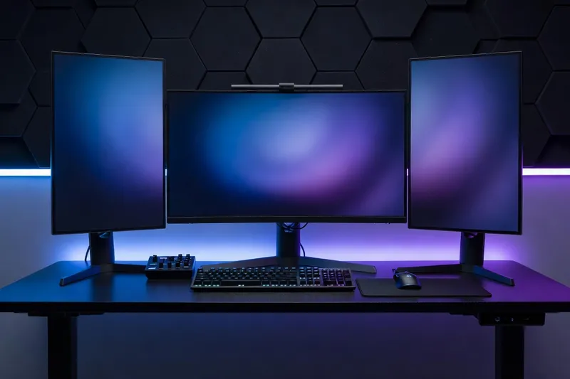 Triple-monitor desk setup with central ultrawide and two side displays in a gaming workstation